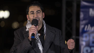 Mohsen Mahdawi speaks into a microphone during an event