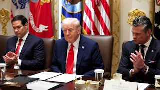 Donald Trump smiles smugly in a Cabinet meeting as Secretary of State Marco Rubio and Defense Secretary Pete Hegseth, seated on both sides of him, clap.