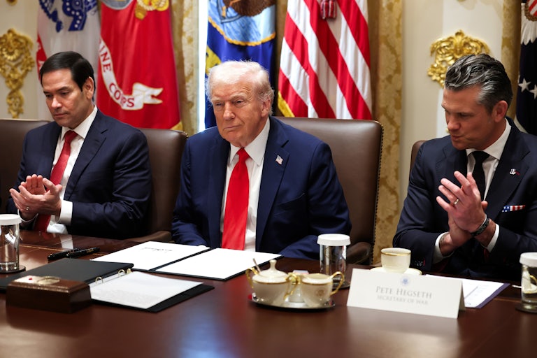 Donald Trump smiles smugly in a Cabinet meeting as Secretary of State Marco Rubio and Defense Secretary Pete Hegseth, seated on both sides of him, clap.