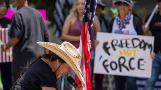 A woman holds an American flag and prays at an anti-vaccine rally in Los Angeles.