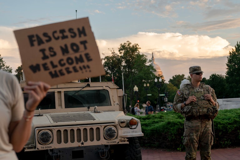 A person holds a sign that says, "Fascism is not welcome here" near a National Guard member outside Union Station in Washington, D.C.