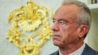 Robert F. Kennedy Jr. stands in front of a gold embellishment on the wall of the White House Oval Office.