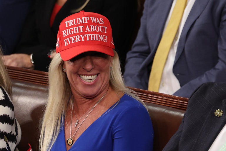 Marjorie Taylor Greene sports a particularly orange spray tan and a red cap reading "Trump was right about everything."