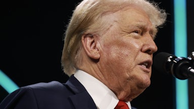 Donald Trump frowns while speaking into a microphone