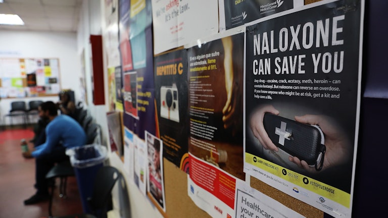 A sign for Naloxone hangs on a wall