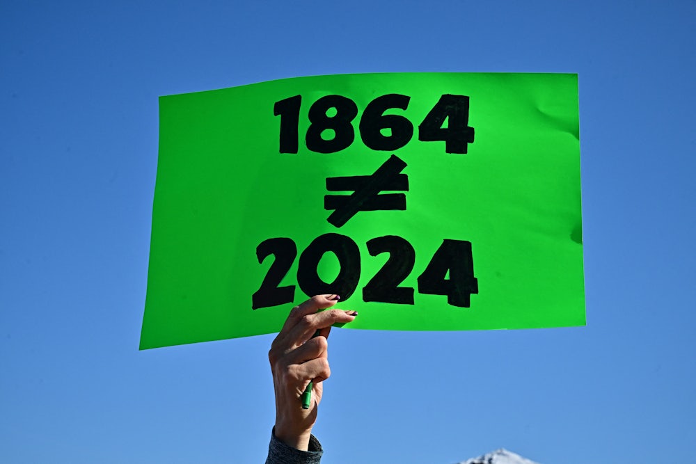 A protestor holds a sign reading 1864 does not equal 2024