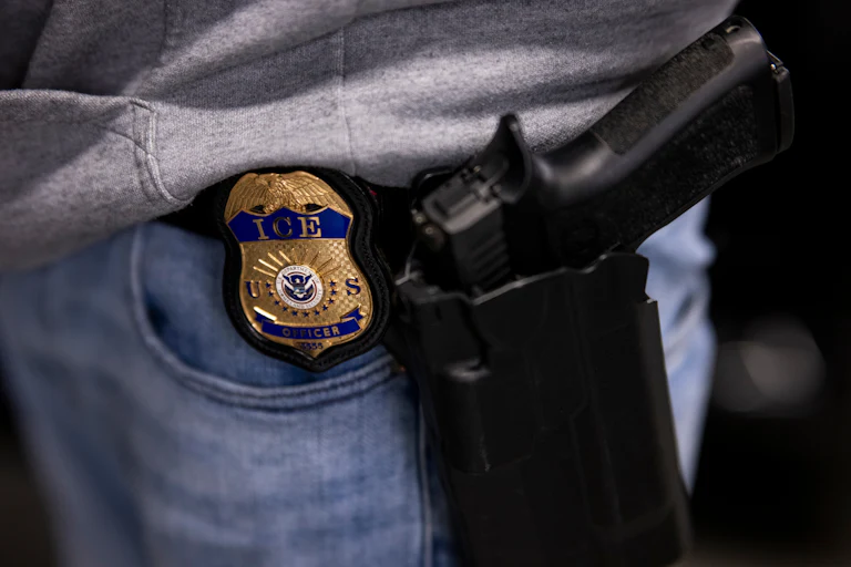 An ICE agent's badge and gun