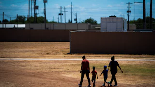 Two immigrant women and two children walk across a field at the South Texas Family Residential Center in Dilley, Texas.