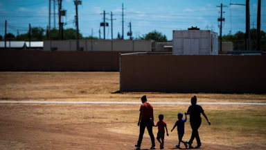 Two immigrant women and two children walk across a field at the South Texas Family Residential Center in Dilley, Texas.