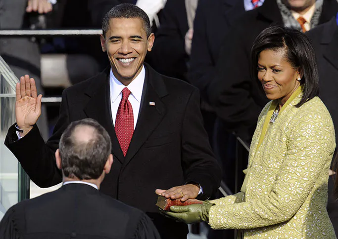 Barack Obama raises his right hand taking the presidential oath of office as Michelle Obama holds the Bible January 2009