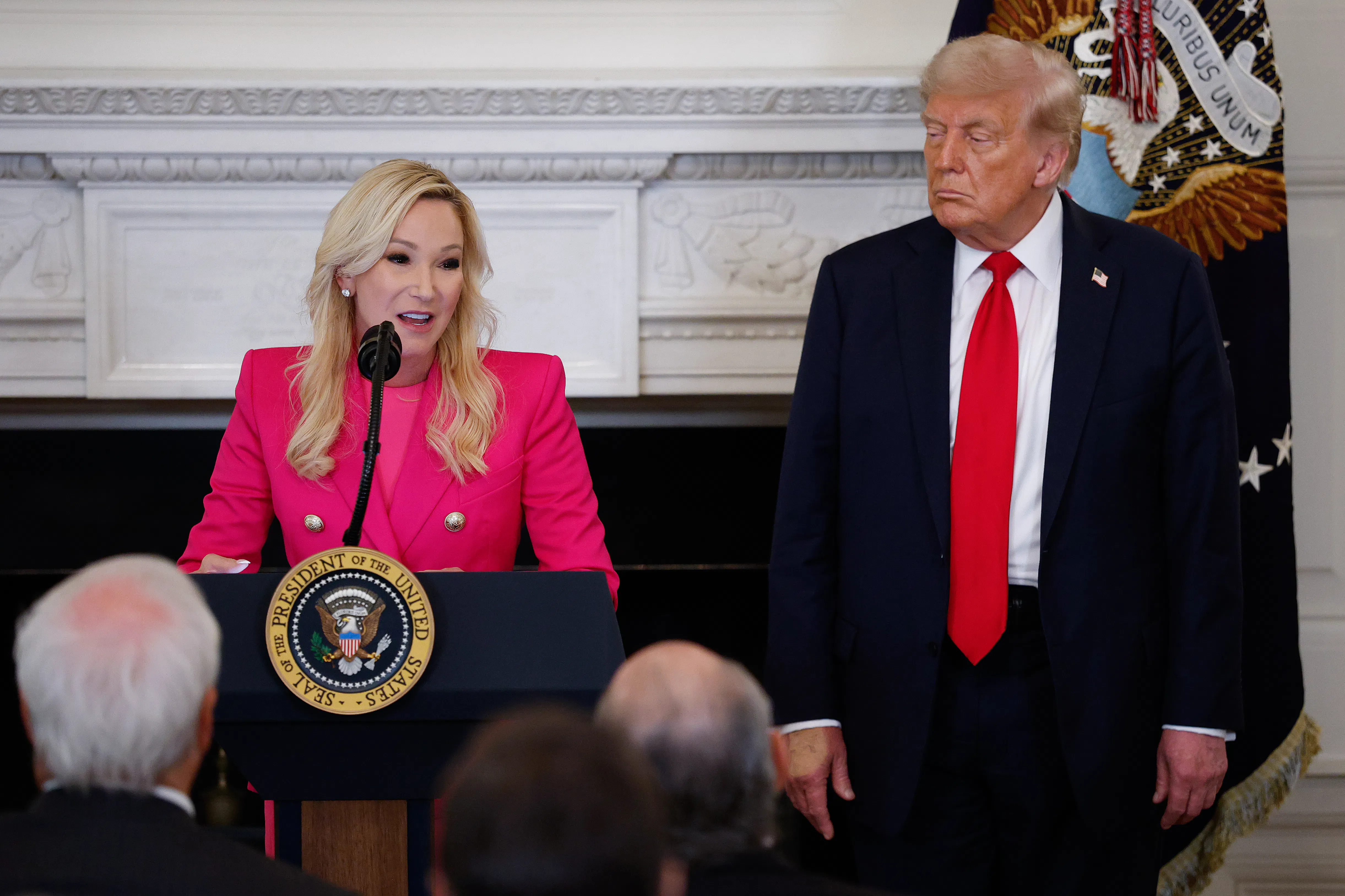 Paula White-Cain speaks at a podium. Donald Trump stands next to her.