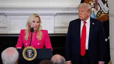Paula White-Cain speaks at a podium. Donald Trump stands next to her.