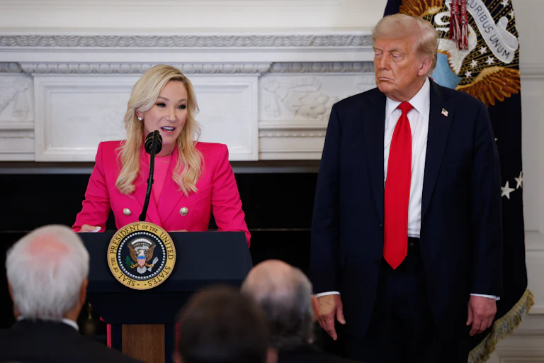 Paula White-Cain speaks at a podium. Donald Trump stands next to her.