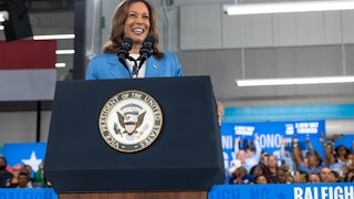 Kamala Harris smiles at a podium with audience members behind her.