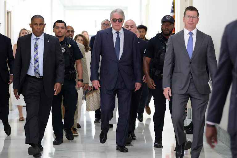 Leon Black walks in a group of people while wearing sunglasses inside