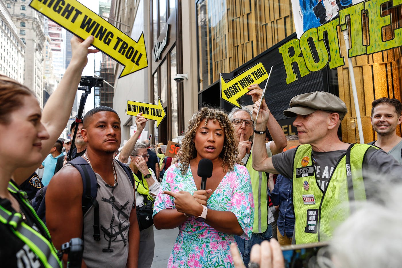 A demonstrator dressed as a fake reporter, with signs labeling her a "Right Wing Troll," takes part in a Labor Day "Workers Over Billionaires" rally outside Trump Tower in New York City on September 1, 2025.