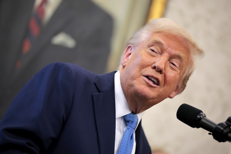 Donald Trump smiles weirdly while standing at a presidential podium.