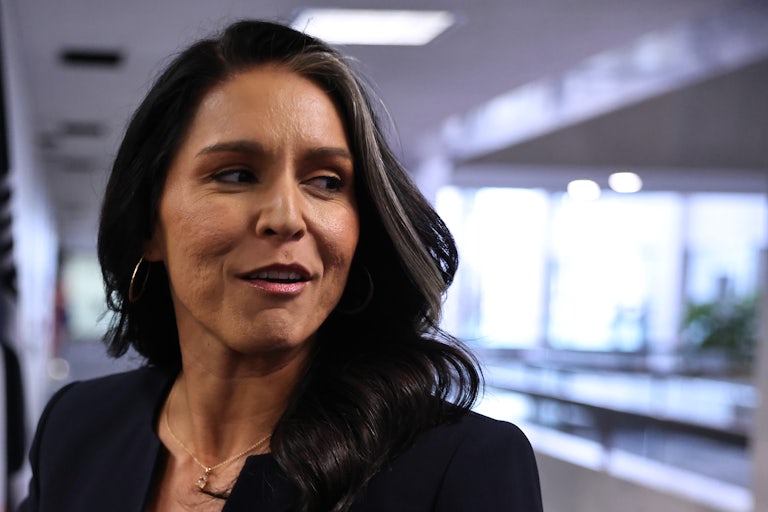 Tulsi Gabbard looks to the side while walking in a Senate building