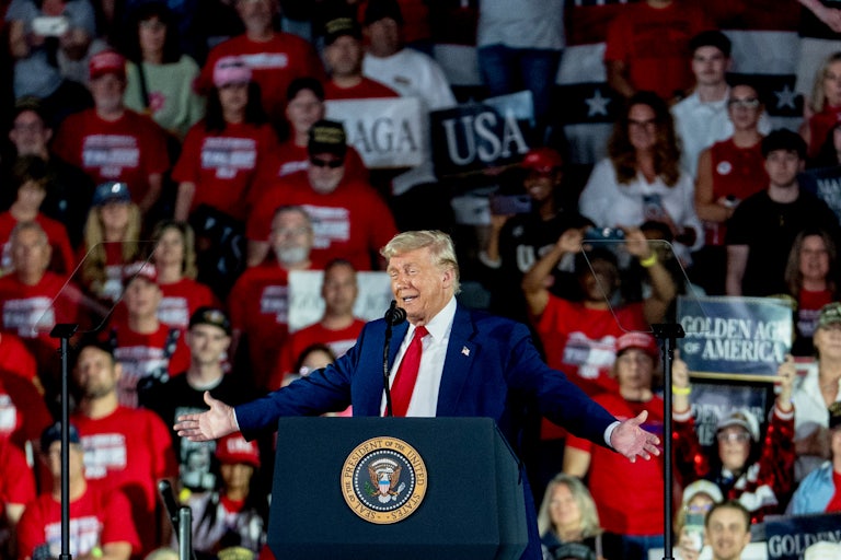 Donald Trump holds his arms out to the side while speaking at a rally