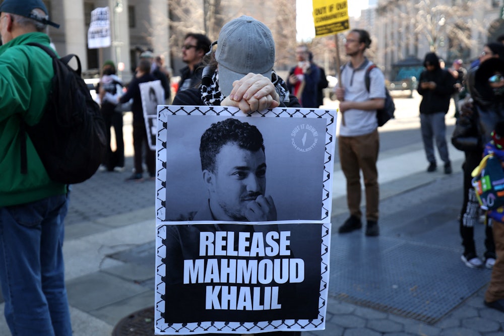 A protester hiding his face holds up a sign saying "release mahmoud Khalil"