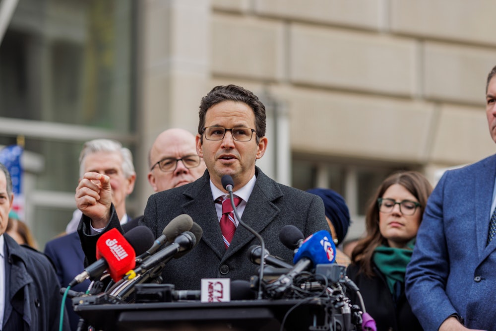Brian Schatz speaks at a podium outside USAID.
