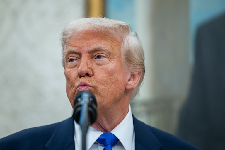 Donald Trump purses his lips while standing in front of a microphone in the Oval Office