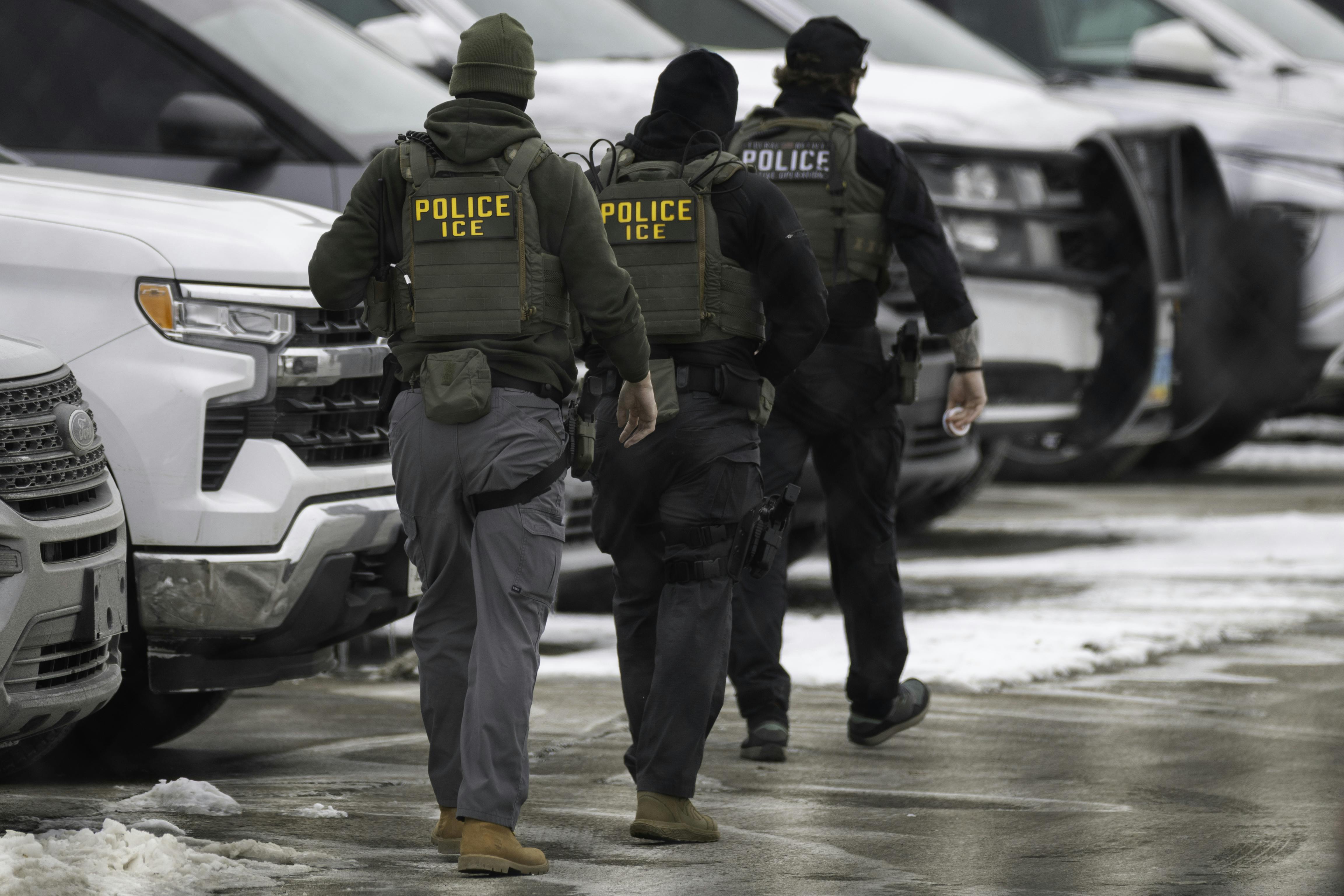 Federal immigration agents walk in a parking lot in Minneapolis, Minnesota