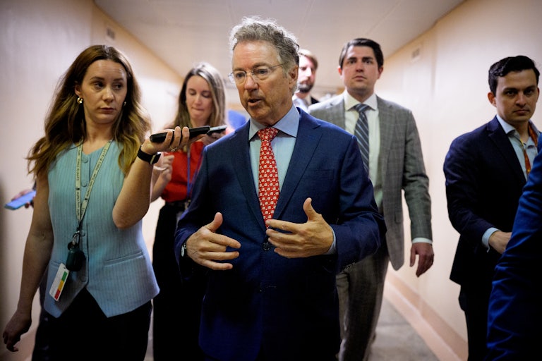 Senator Rand Paul speaks to reporters while walking in the Capitol.