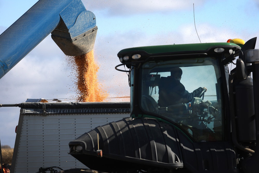 A machine funnels corn kernels into another machine.
