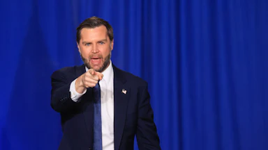Vice President JD Vance points and opens his mouth while walking off stage after an event