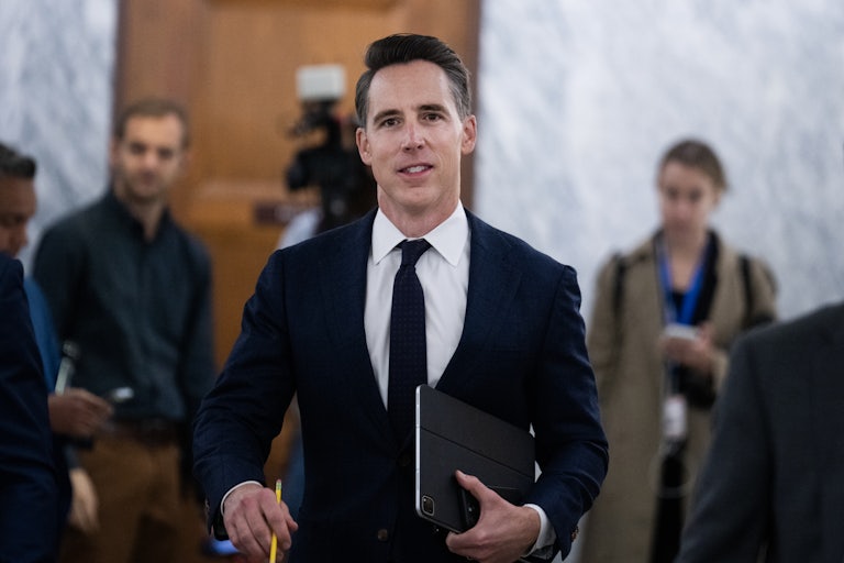 Josh Hawley holds an iPad under his arm while walking in the Capitol