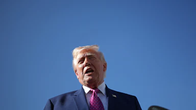 President Donald Trump speaking into a mic outdoors
