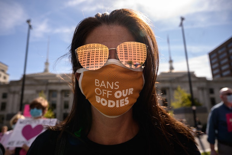 a women's rights protester wears a mask reading "bans off our bodies"