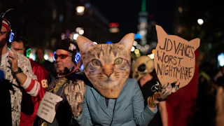 Someone with a cat mask holds a sign reading "JD Vance's Worst Nightmare."