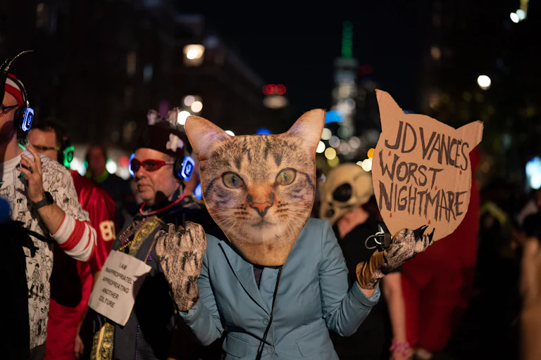Someone with a cat mask holds a sign reading "JD Vance's Worst Nightmare."