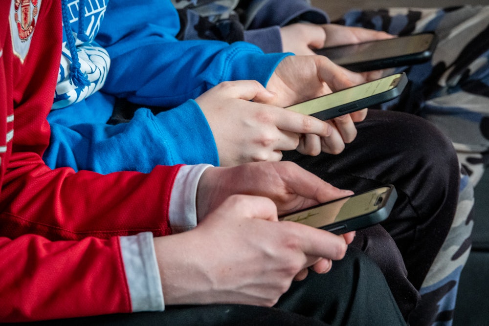 Three teenage boys looking at their smartphone screens, April 2025 in St Jean d'Aulps, France