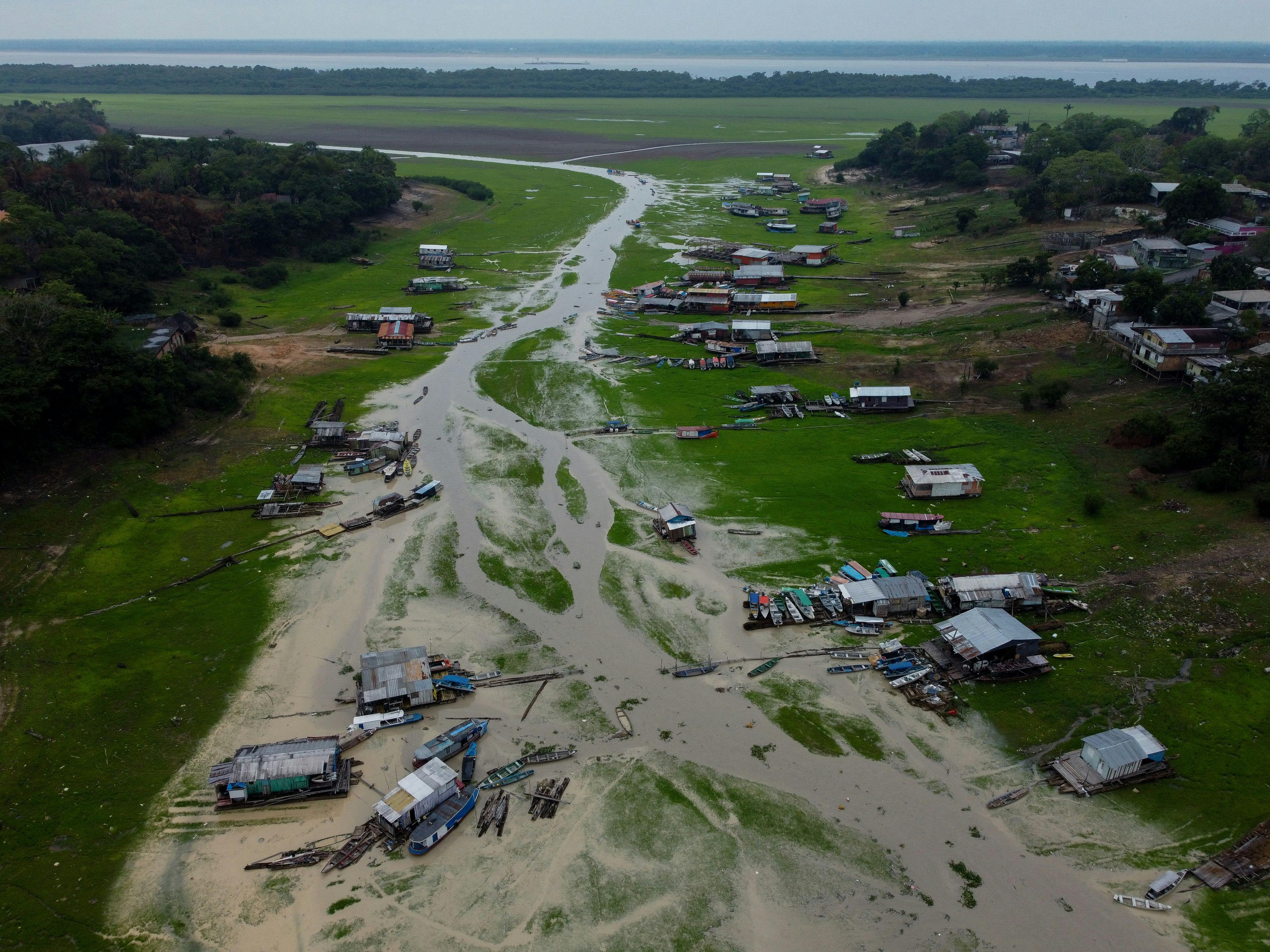 An aerial view shows houses and boats on a riverbed.