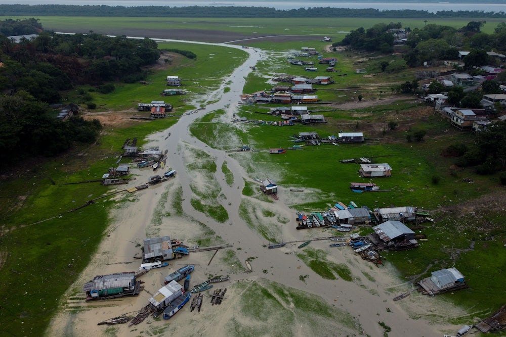 An aerial view shows houses and boats on a riverbed.