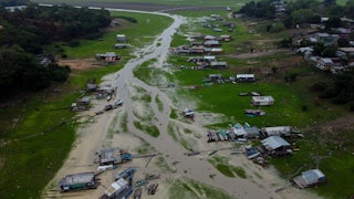 An aerial view shows houses and boats on a riverbed.
