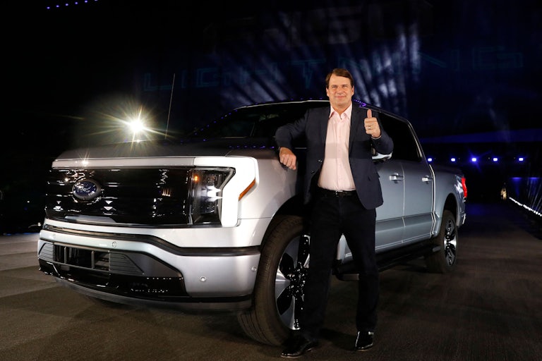 Jim Farley leans on a massive pickup truck while giving the camera a thumbs up.