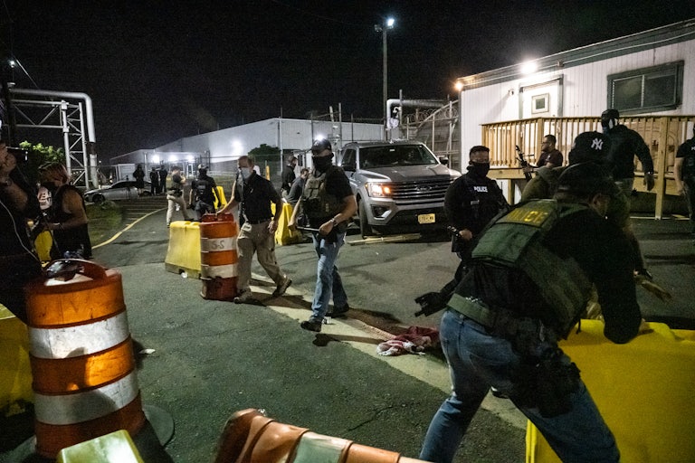 Police officers clear a path for a car leaving from Delaney Hall. They are all wearing face masks.