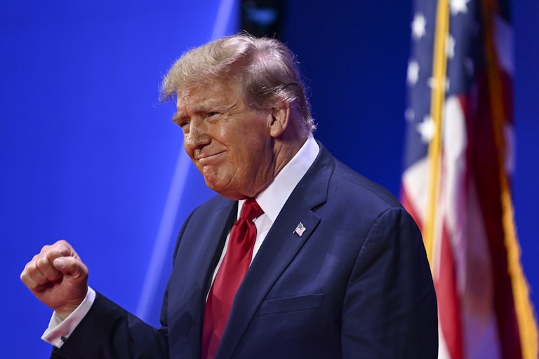 Donald Trump smiles weirdly and raises a closed fist as if in victory