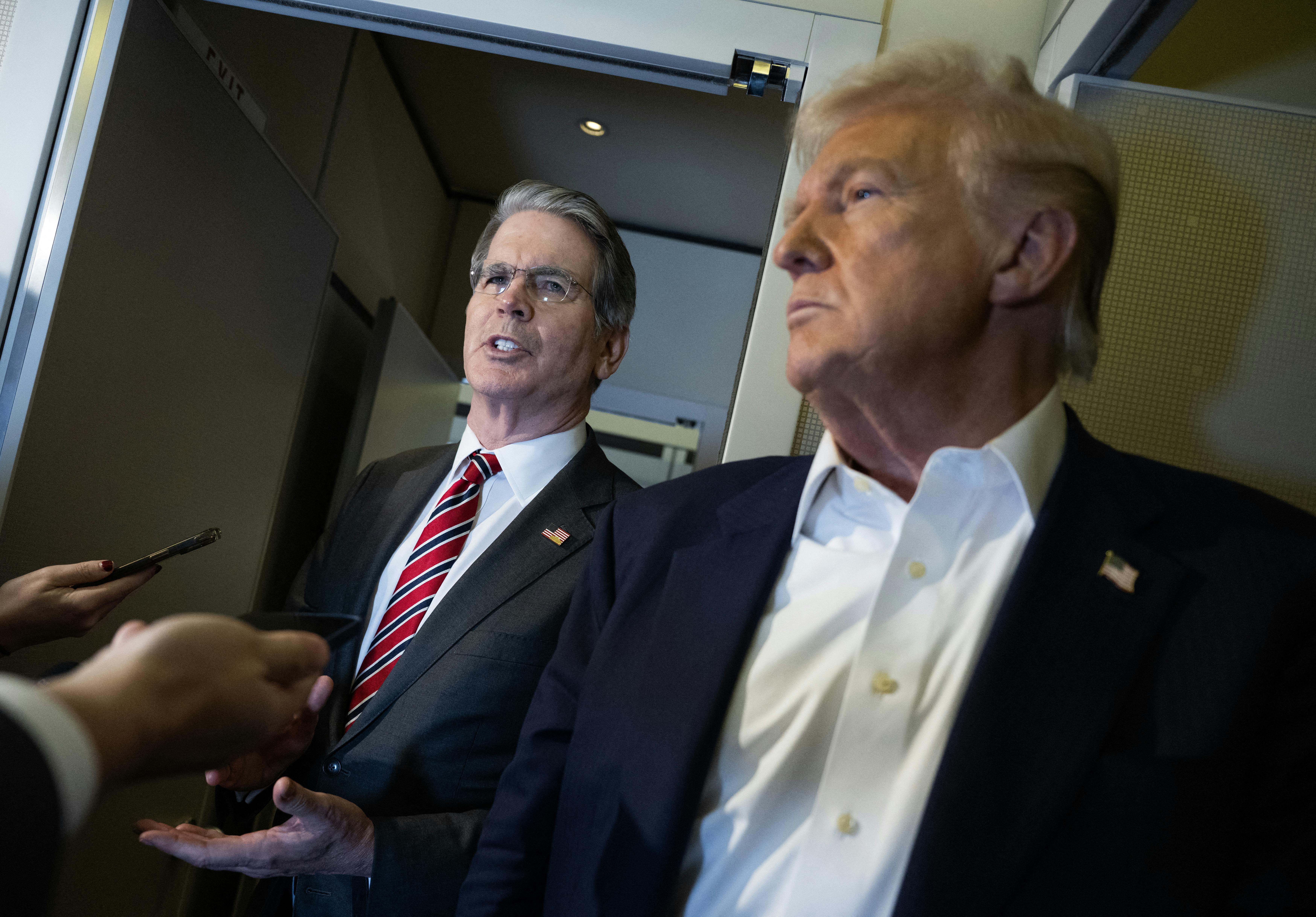 Treasury Secretary Scott Bessent stands next to Donald Trump while speaking to reporters on Air Force One