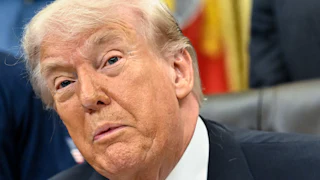 Donald Trump speaks while sitting at his desk in the Oval Office