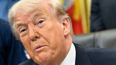 Donald Trump speaks while sitting at his desk in the Oval Office