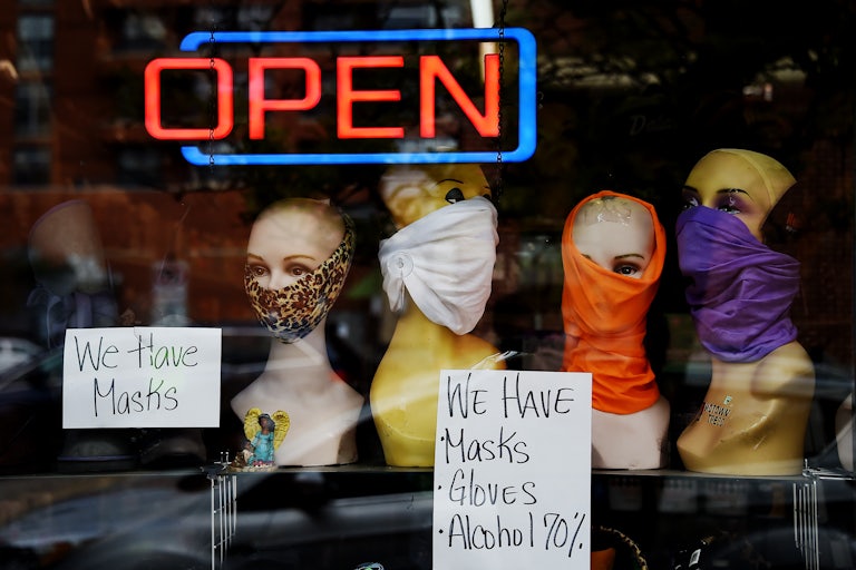 Mannequin heads wear masks in the window of a small boutique