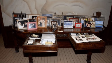 A coffee table full of framed photos, including one of Donald Trump, Melania Trump, and Jeffrey Epstein.