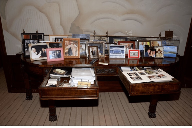 A coffee table full of framed photos, including one of Donald Trump, Melania Trump, and Jeffrey Epstein.