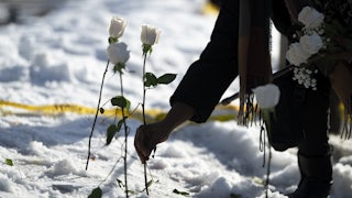 A person puts a white rose in the snow where a person was shot dead by an ICE agent in Minneapolis, Minnesota