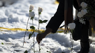A person puts a white rose in the snow where a person was shot dead by an ICE agent in Minneapolis, Minnesota